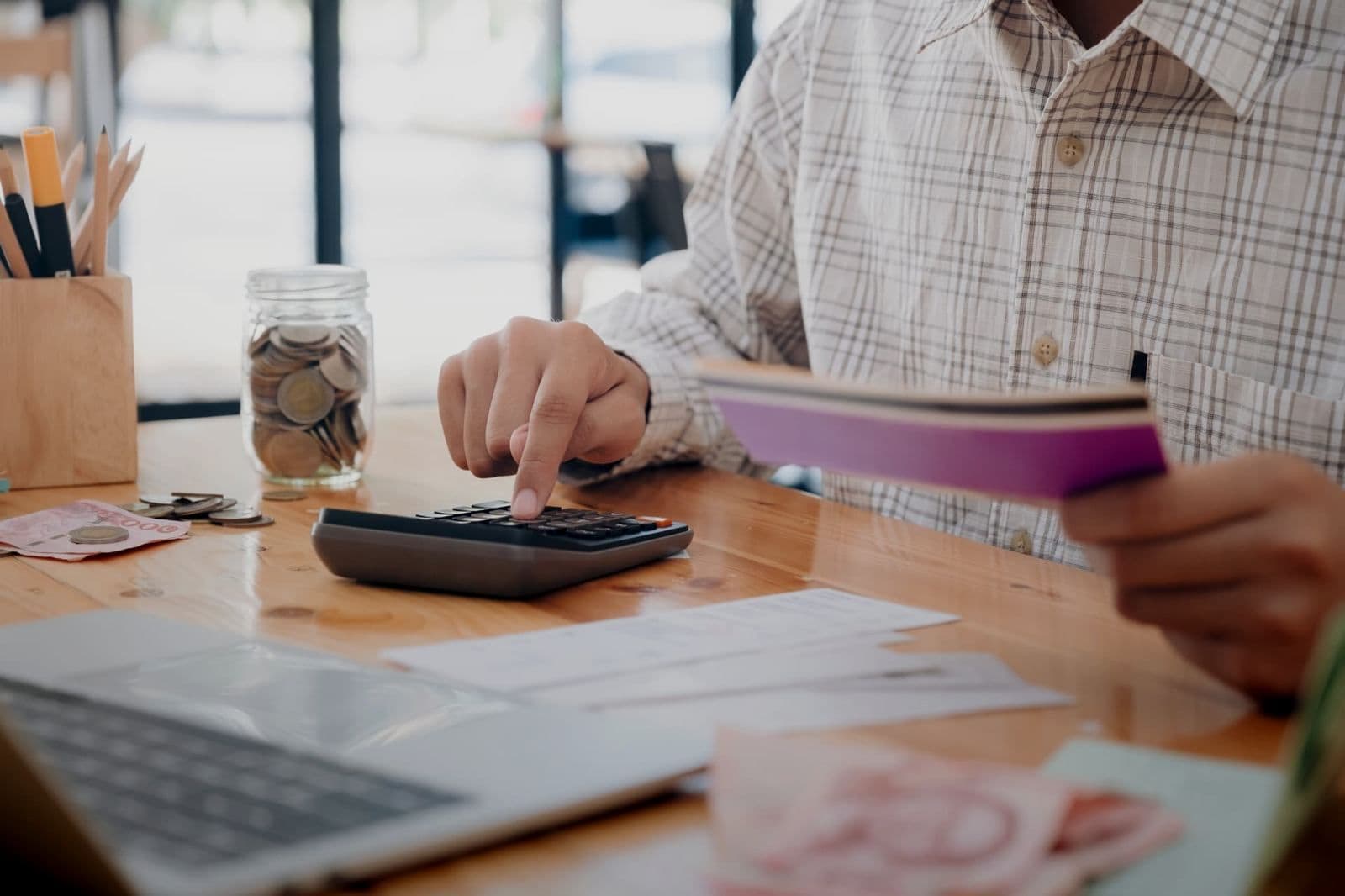 Bookkeeper using a calculator and bankbook at a wooden desk