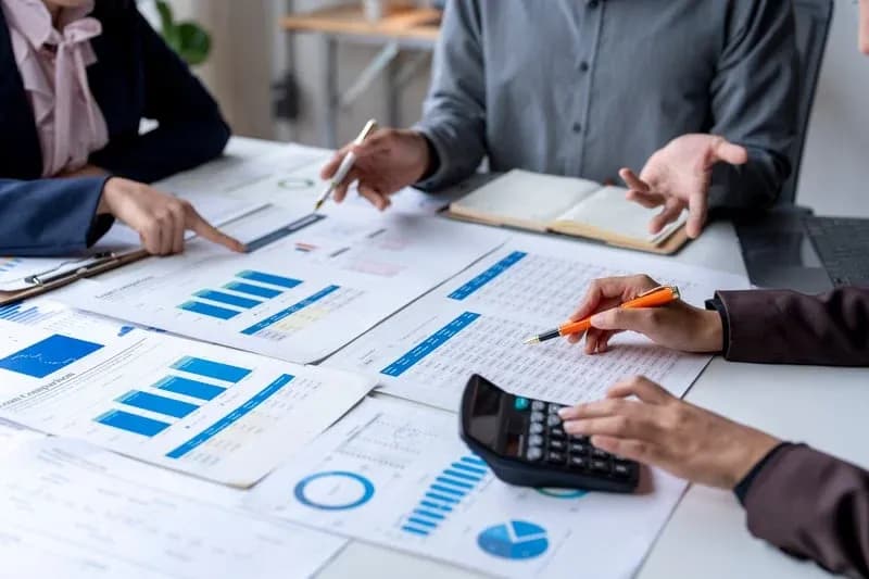 Three professionals reviewing financial charts and loan comparisons with calculators — Professional Bookkeeping Plan from RDP Bookkeeping Solutions