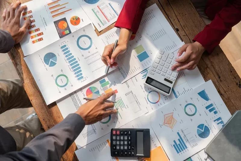 Two people collaborating over financial reports and charts with calculators — Standard Bookkeeping Plan from RDP Bookkeeping Solutions